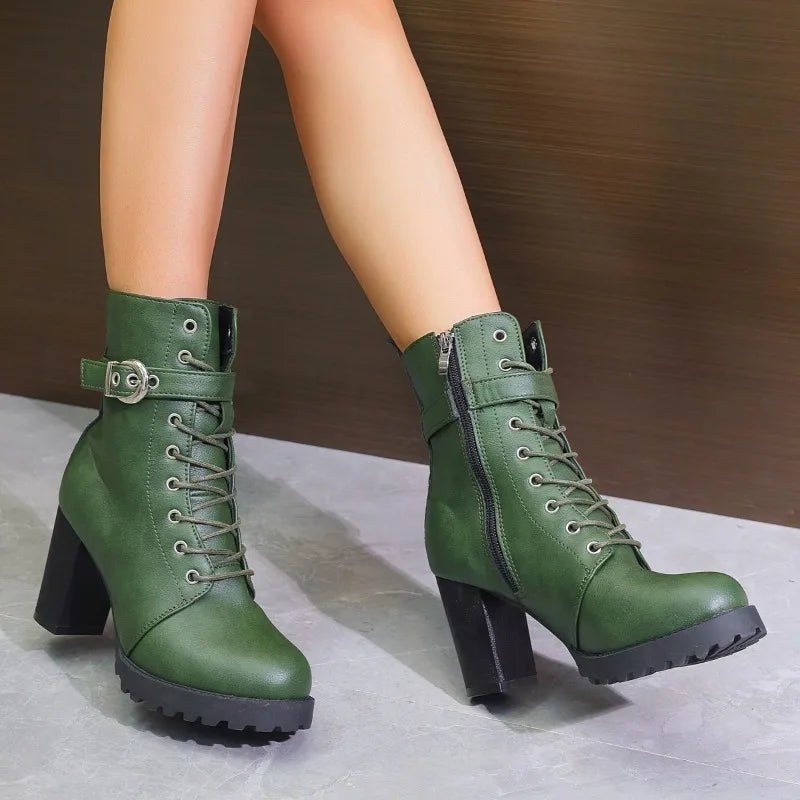 Green lace-up ankle boots with buckle strap and block heel, side view on a tiled floor