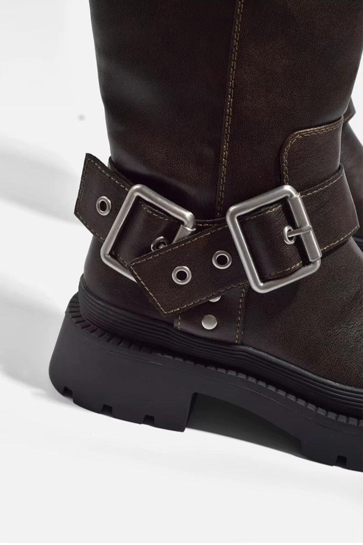 Close-up of the square metal buckles, eyelets and studs on a brown biker boot
