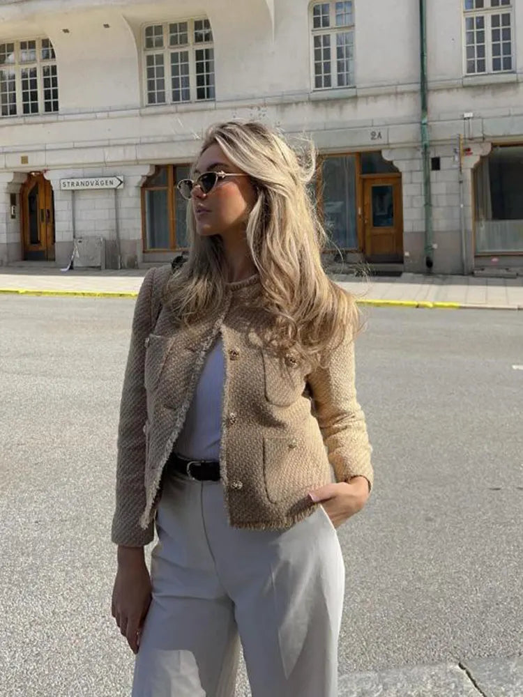 Beige tweed jacket with patch pockets styled with a belt and gray pants