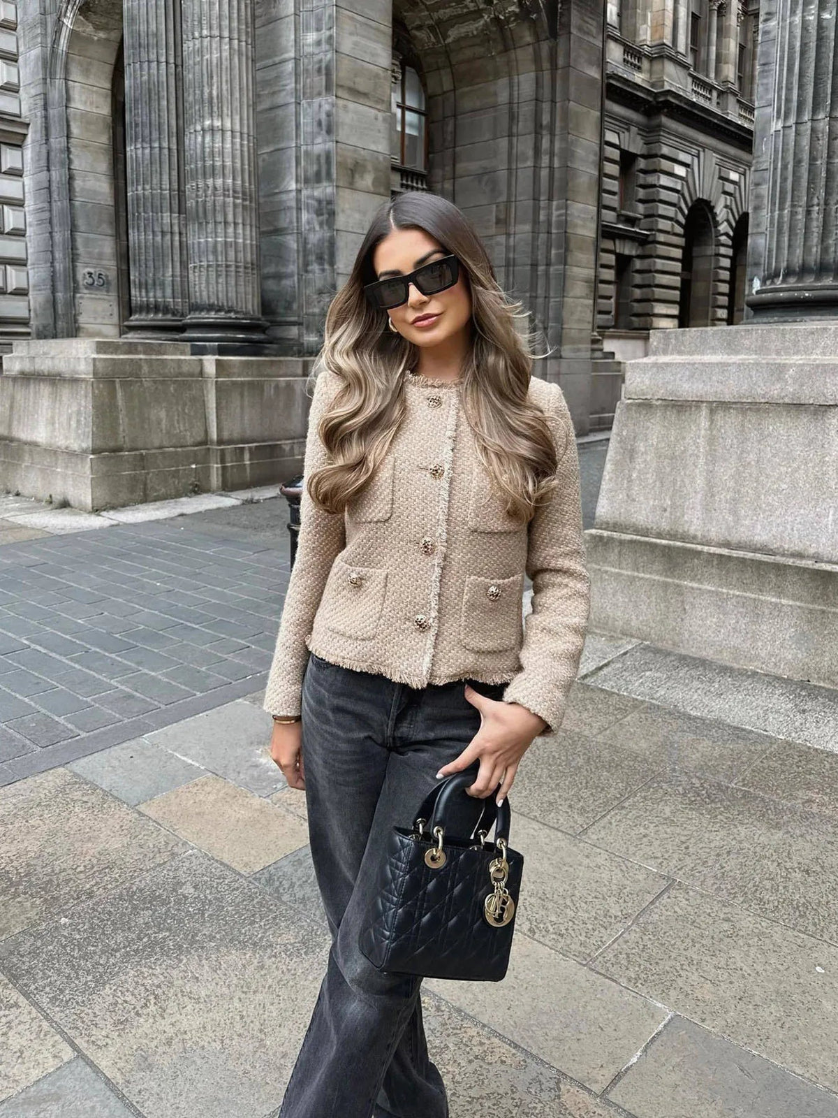 Beige tweed jacket buttoned up and worn with black leather pants