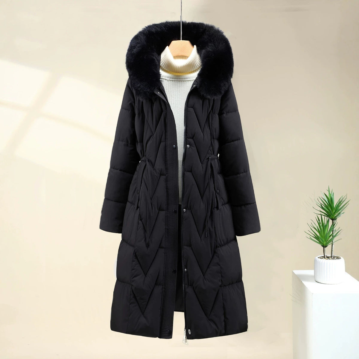 Black chevron quilted long parka with faux fur hood, front view on a hanger