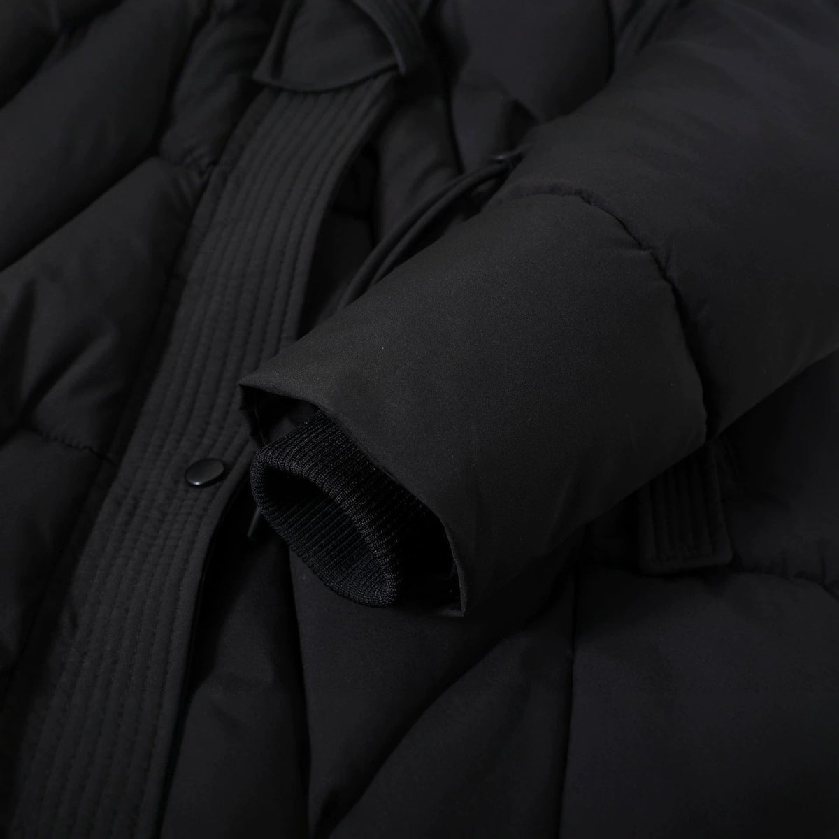 Close up of the black parka zip, drawstring and ribbed inner cuff