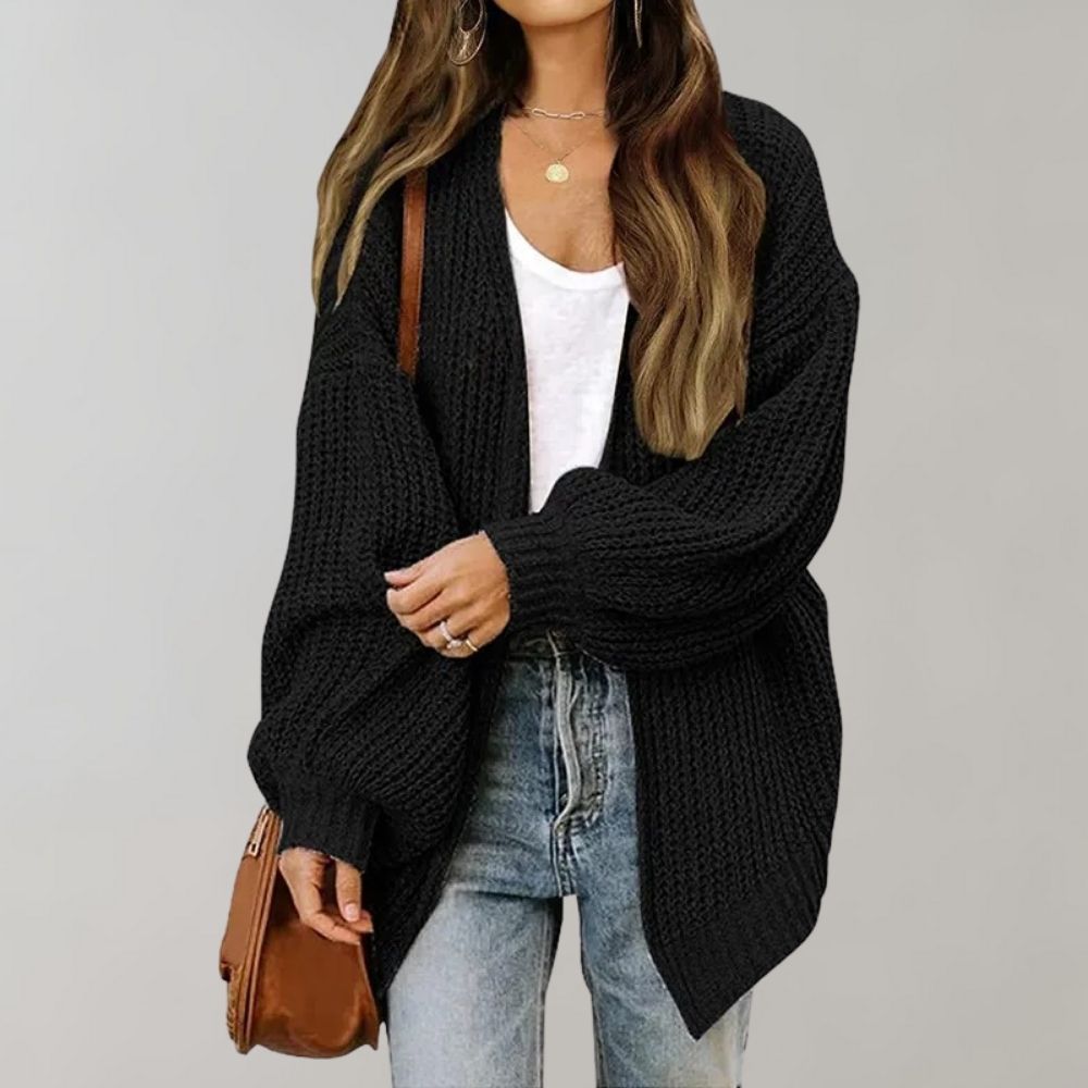 Black chunky knit cocoon cardigan worn open over a white tee and jeans, front view