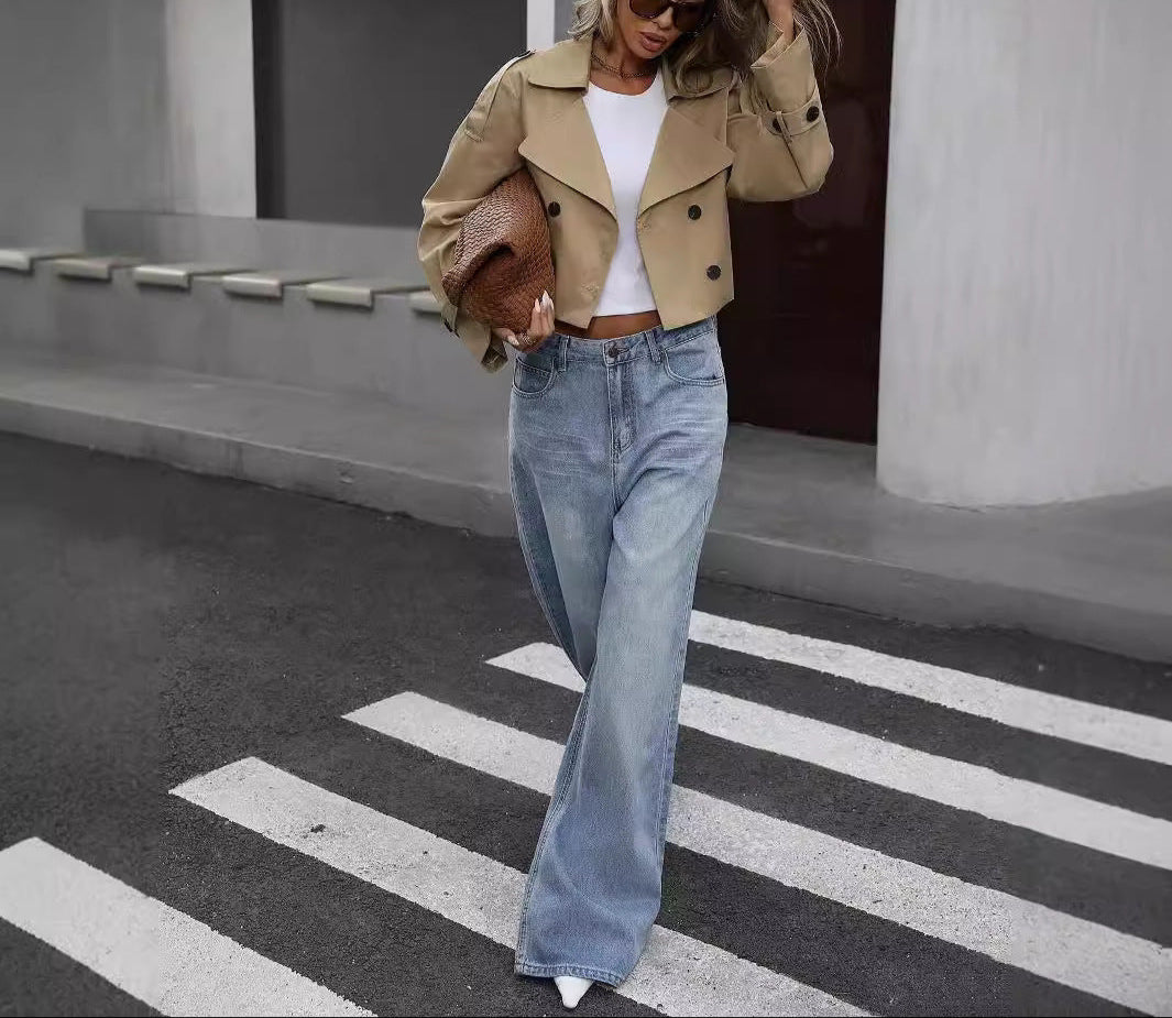 Khaki cropped trench jacket worn with wide leg jeans on a crosswalk