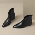 Pair of black V cut ankle boots with pointed toe, angled view