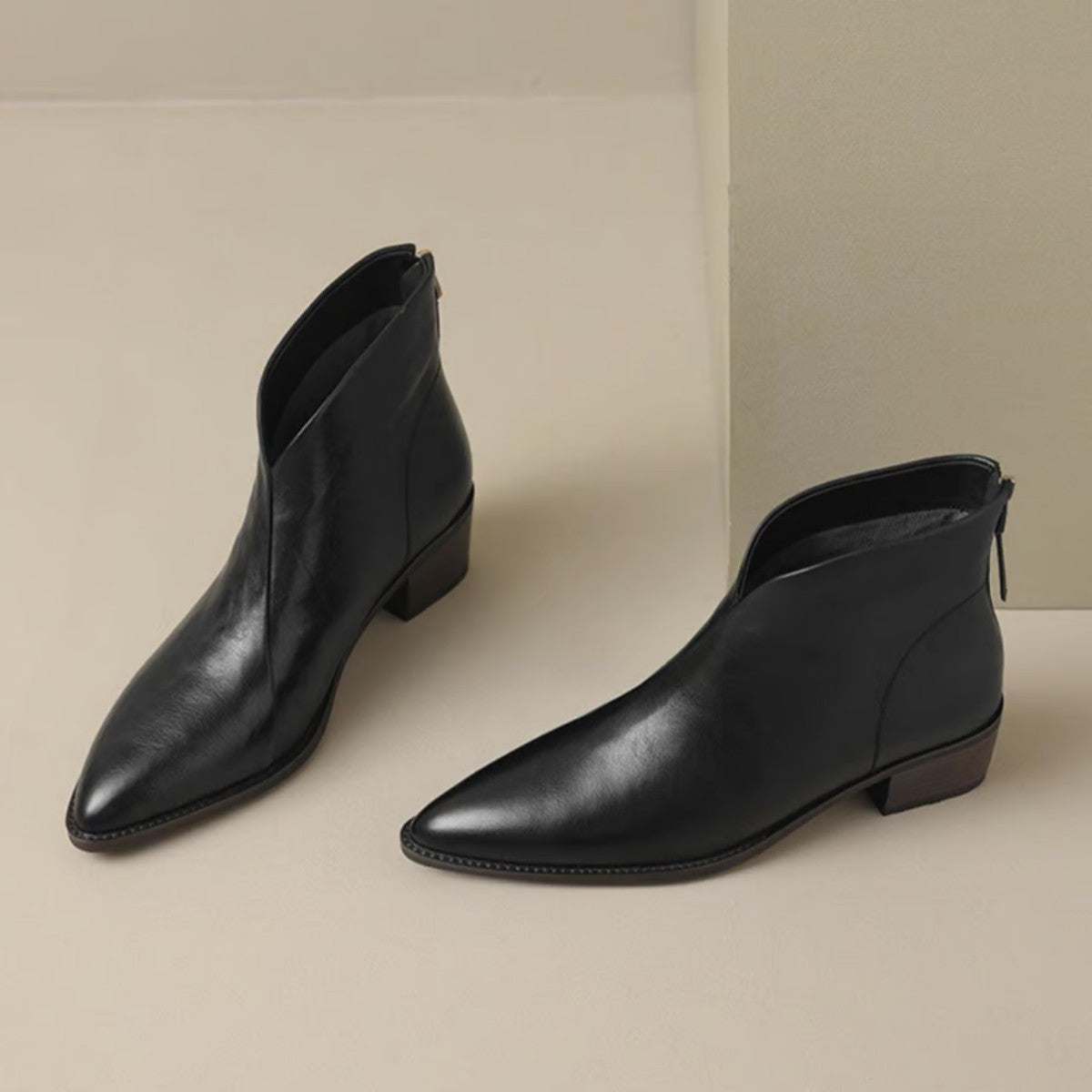 Pair of black V cut ankle boots with pointed toe, angled view