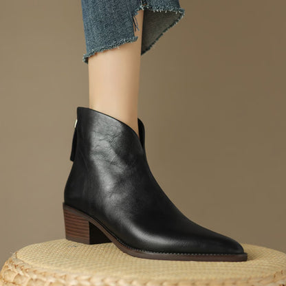Black V cut ankle boot on foot standing on a woven stool