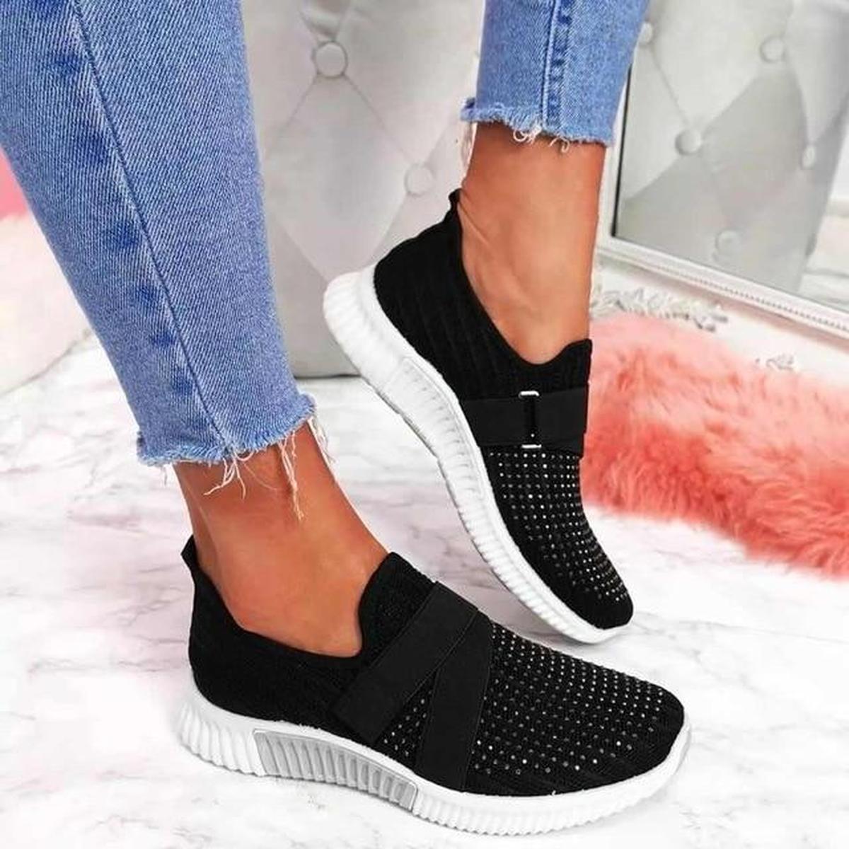 Black elastic strap sneakers with a studded toe and white sole, worn with cropped jeans