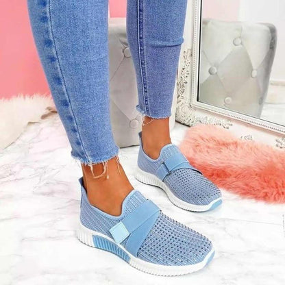 Blue elastic strap sneakers with a studded toe, worn with cropped jeans, front view