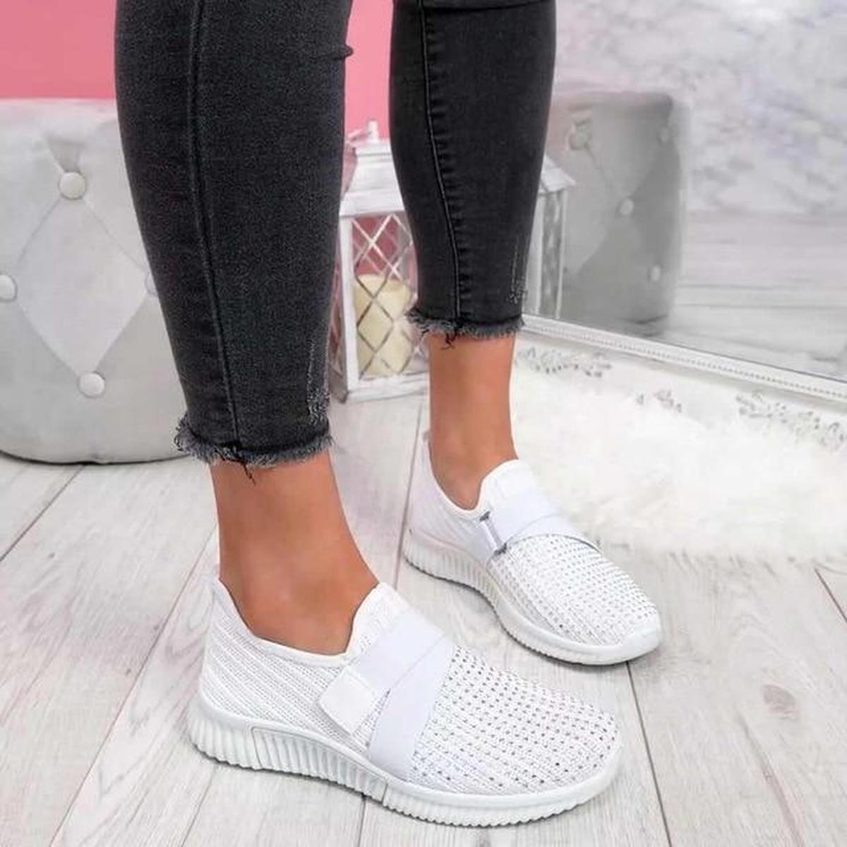 White elastic strap sneakers with a studded toe, worn with black skinny jeans