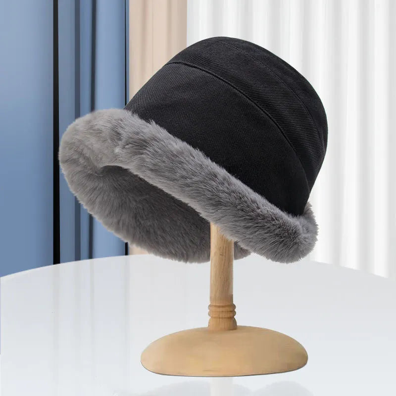 Black bucket hat with a gray faux fur brim on a hat stand