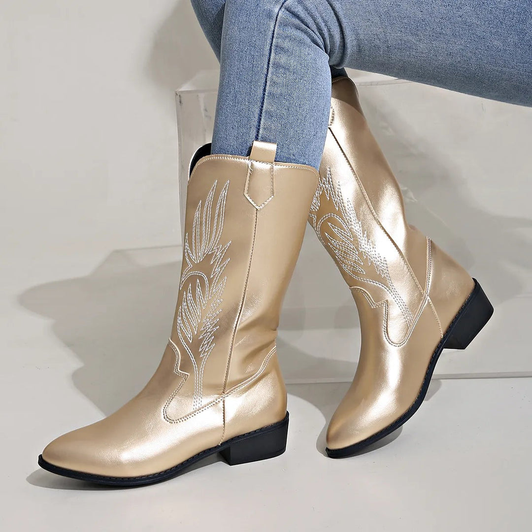 Gold metallic cowboy boots with feather embroidery, worn with jeans