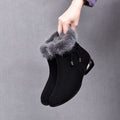 Black suede bootie with faux fur cuff held by hand
