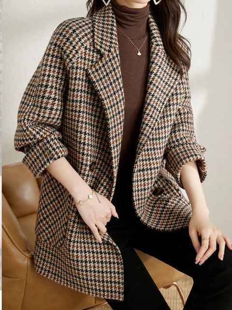 Brown houndstooth check blazer worn open over a turtleneck, seated front view