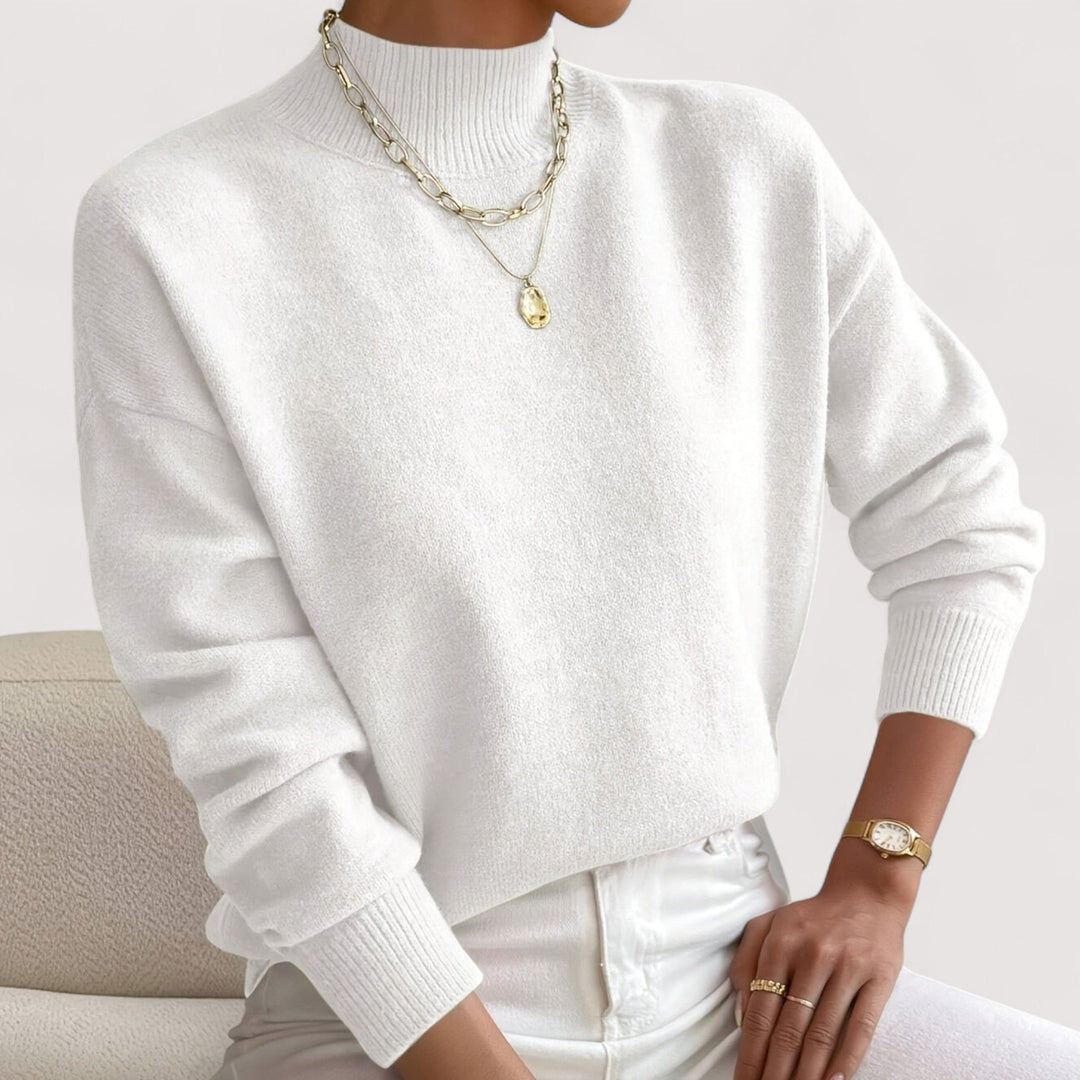 White soft knit sweater with a mock neck and ribbed cuffs, worn with white jeans