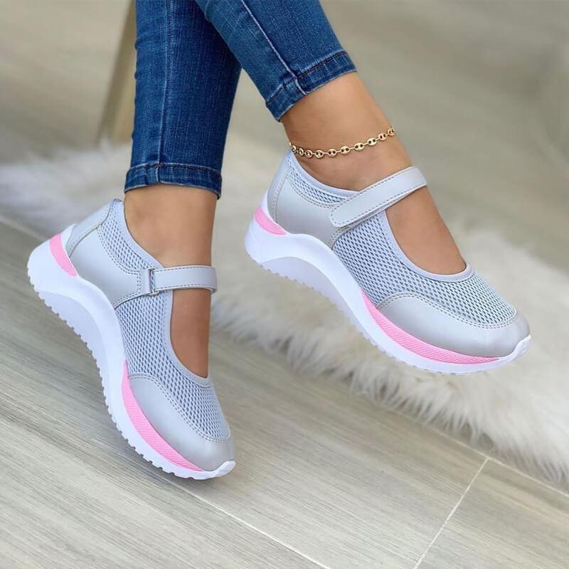 Gray mesh strap sneakers with a pink sole stripe, worn with skinny jeans, side view