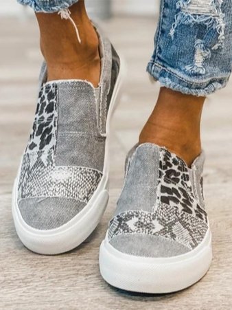 Grey patchwork slip-on sneakers with leopard and snake print panels, worn with jeans