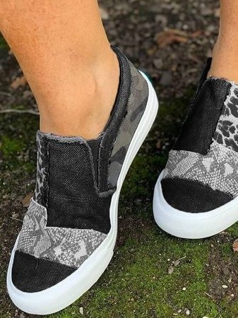 Black patchwork slip-on sneakers with camo and snake print panels, worn outdoors