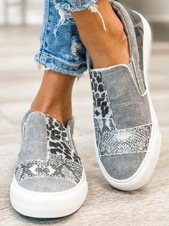 Grey patchwork slip-on sneakers with frayed edges, front view on feet