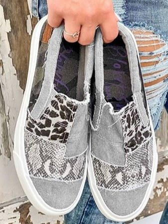 Grey patchwork slip-on sneakers held in hand, top view of the print panels
