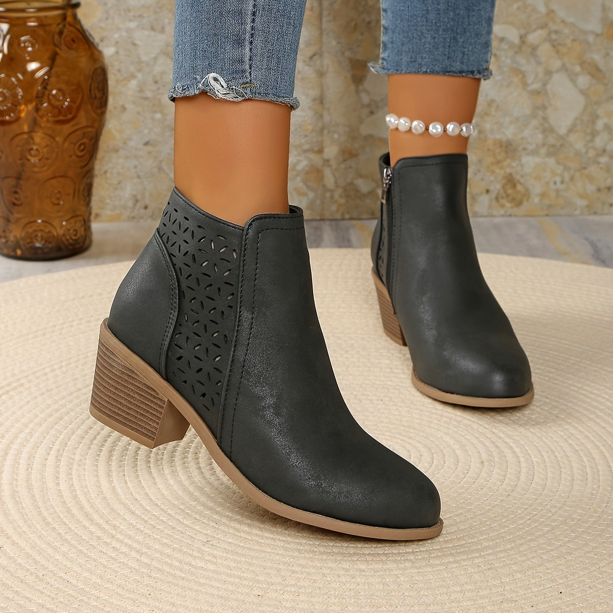 Gray perforated panel ankle boots worn with cropped jeans, angled view