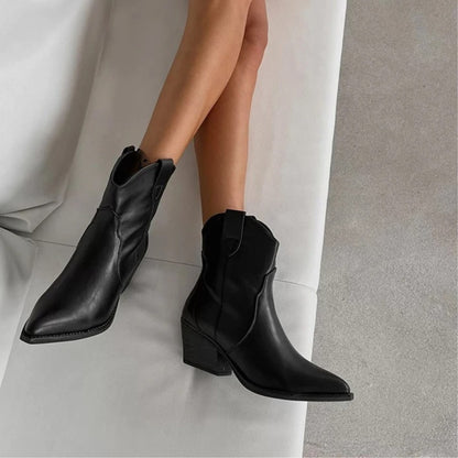 Black pointed toe western ankle boots worn crossed on a sofa