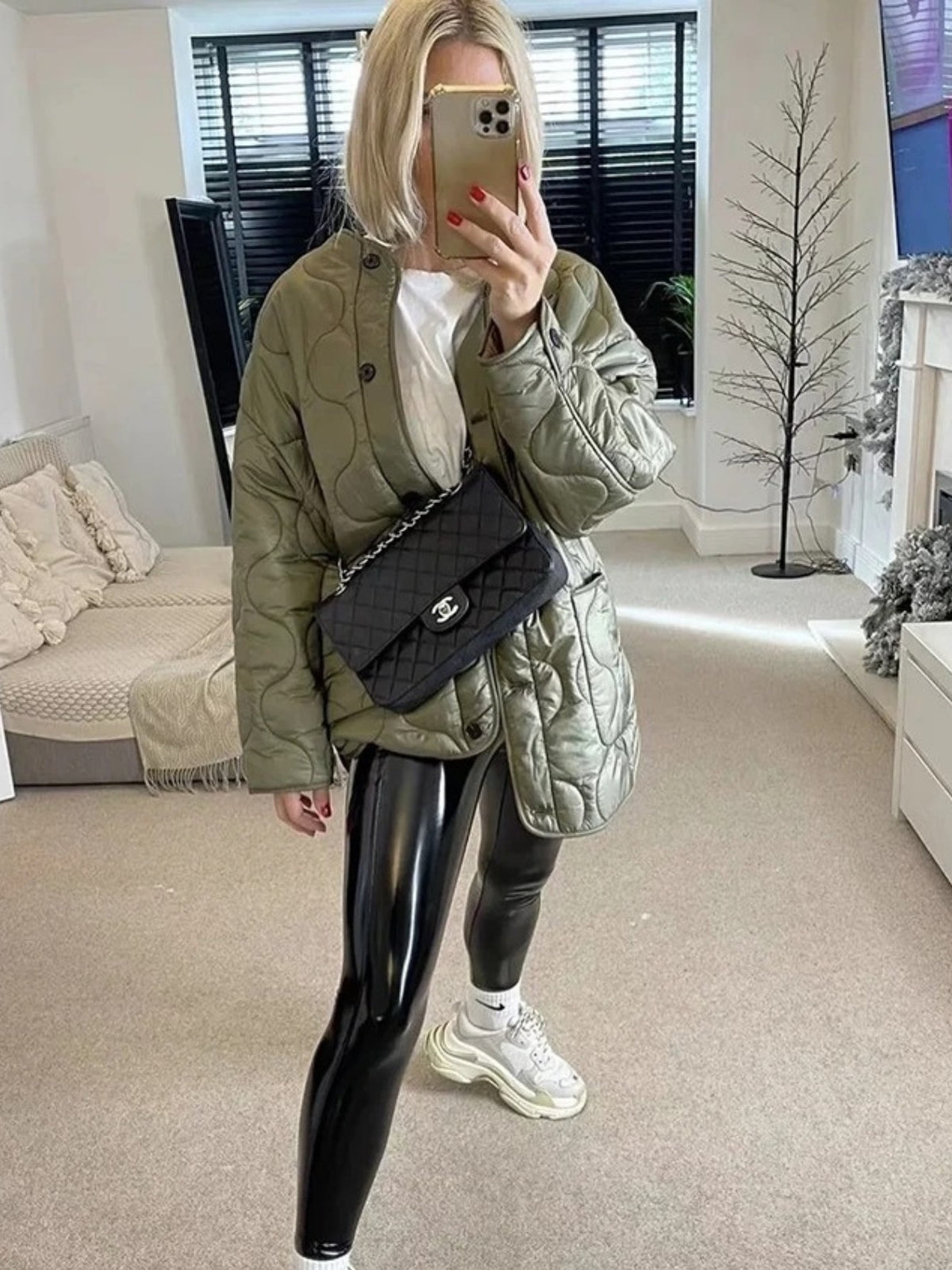 Green quilted collarless jacket worn open over a white top and black leggings