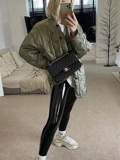 Green quilted jacket with wave stitching worn with leggings and sneakers, side view