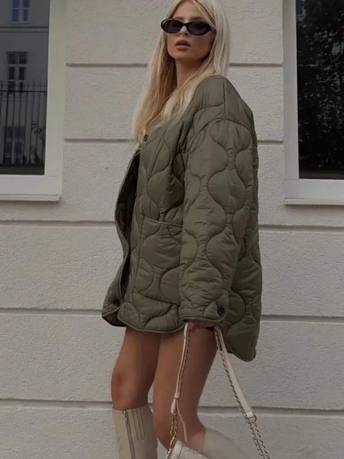 Green quilted jacket worn over a mini dress with knee high boots, street side view