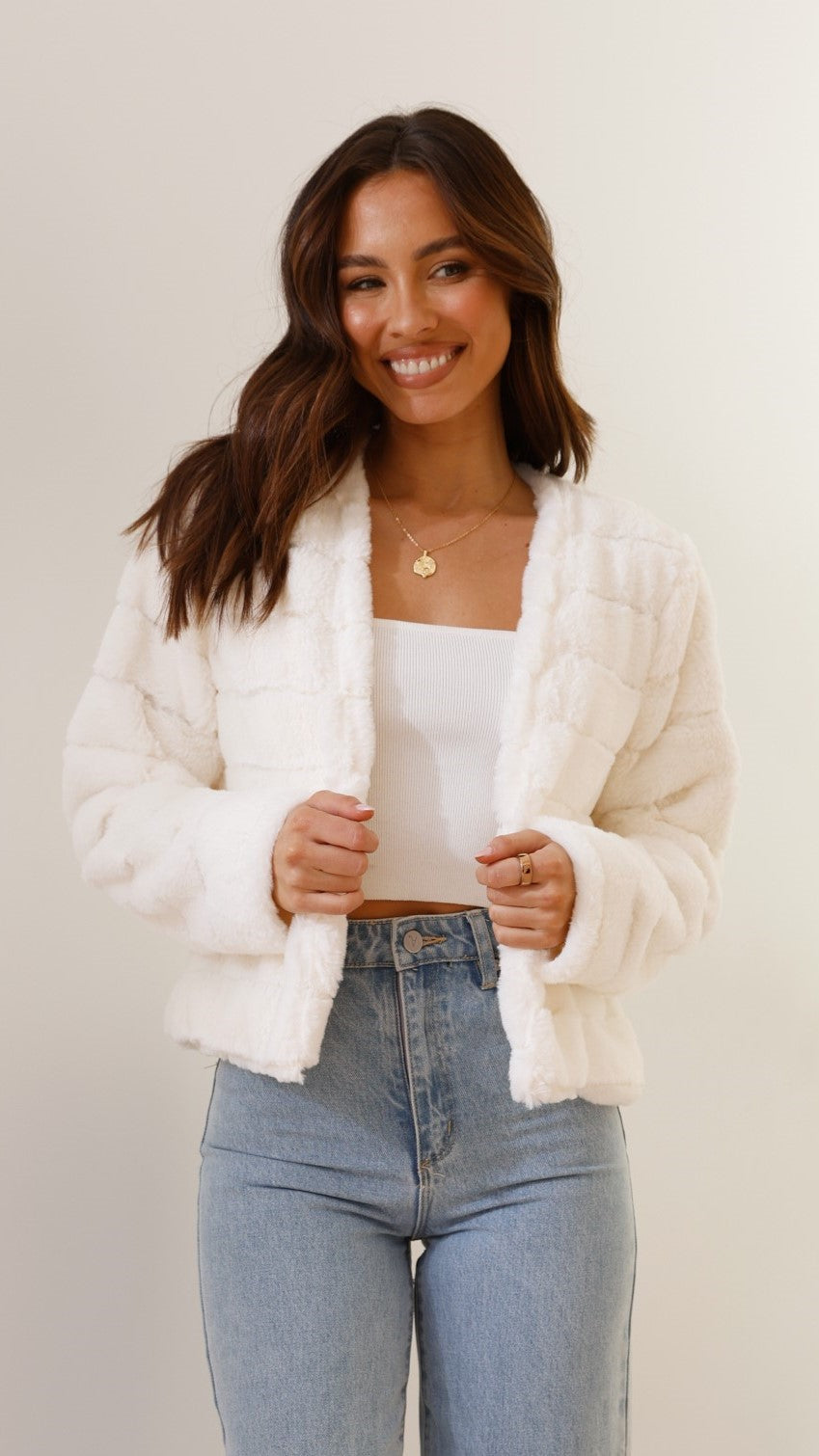 Ivory cropped faux fur open jacket worn with jeans