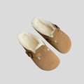 Pair of tan suede clogs with white shearling lining and buckle strap, top view