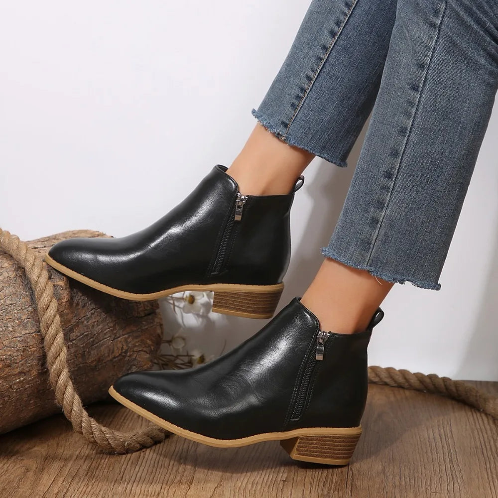 Black side zip ankle boots with a stacked block heel, worn with cropped jeans, side view