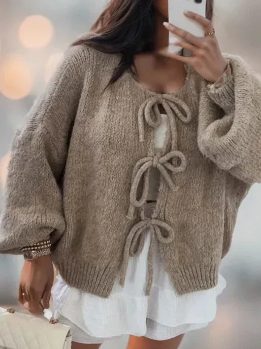 Khaki tie front knit cardigan on a model with a white ruffle skirt, front view