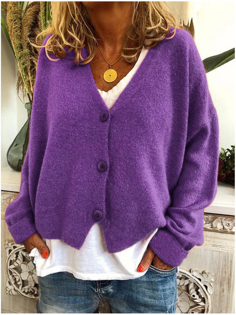 Woman wearing a purple V neck button front cardigan over a white top and light wash jeans