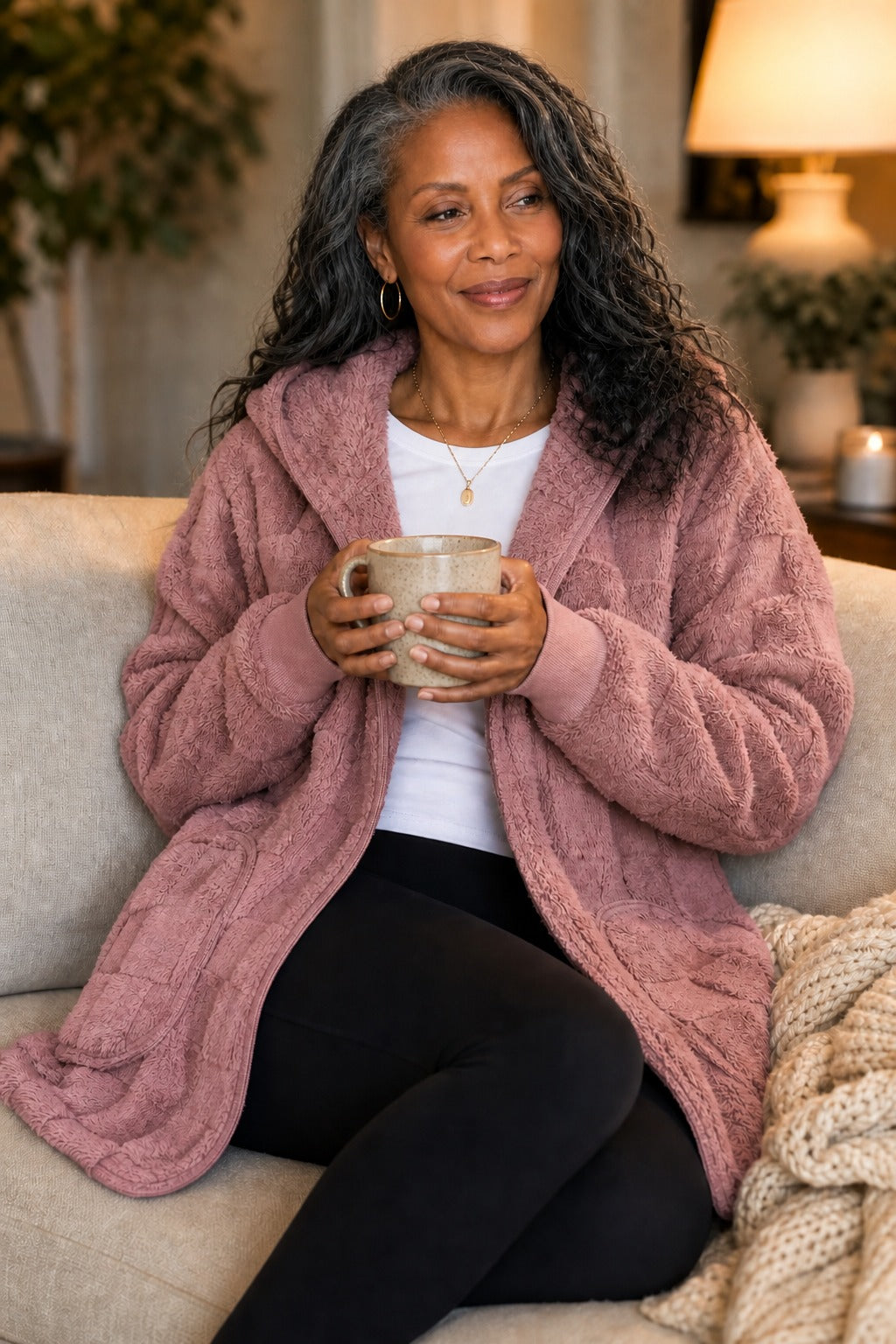 Woman on a sofa with a mug in a dusty pink plush cardigan