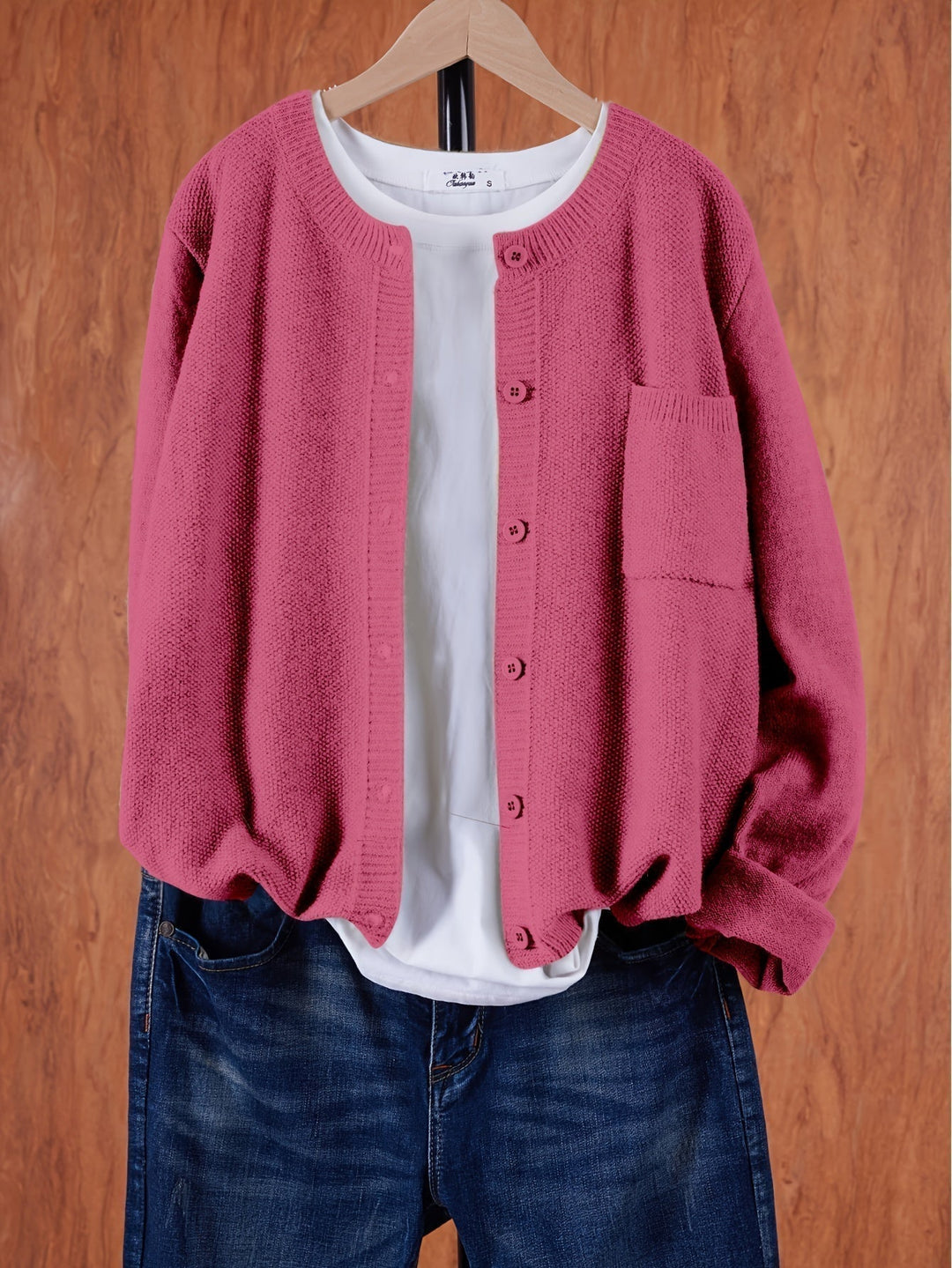 Pink crew neck button cardigan with a chest pocket on a hanger