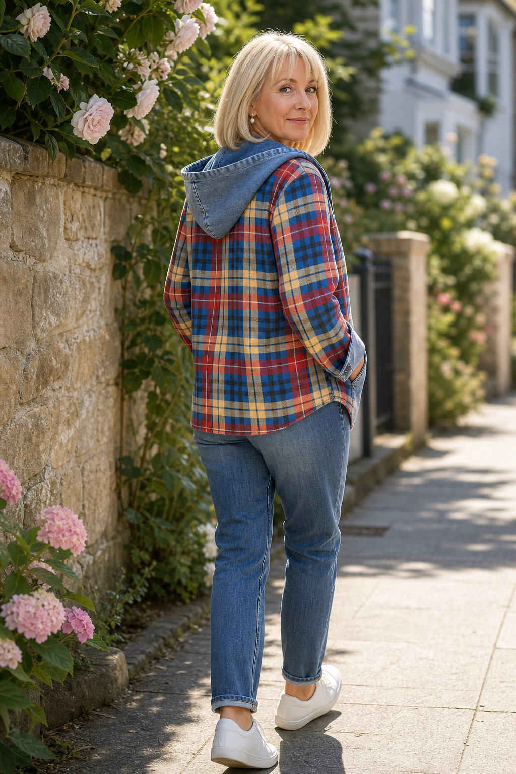 Woman by a stone wall in a plaid hooded denim trim cardigan