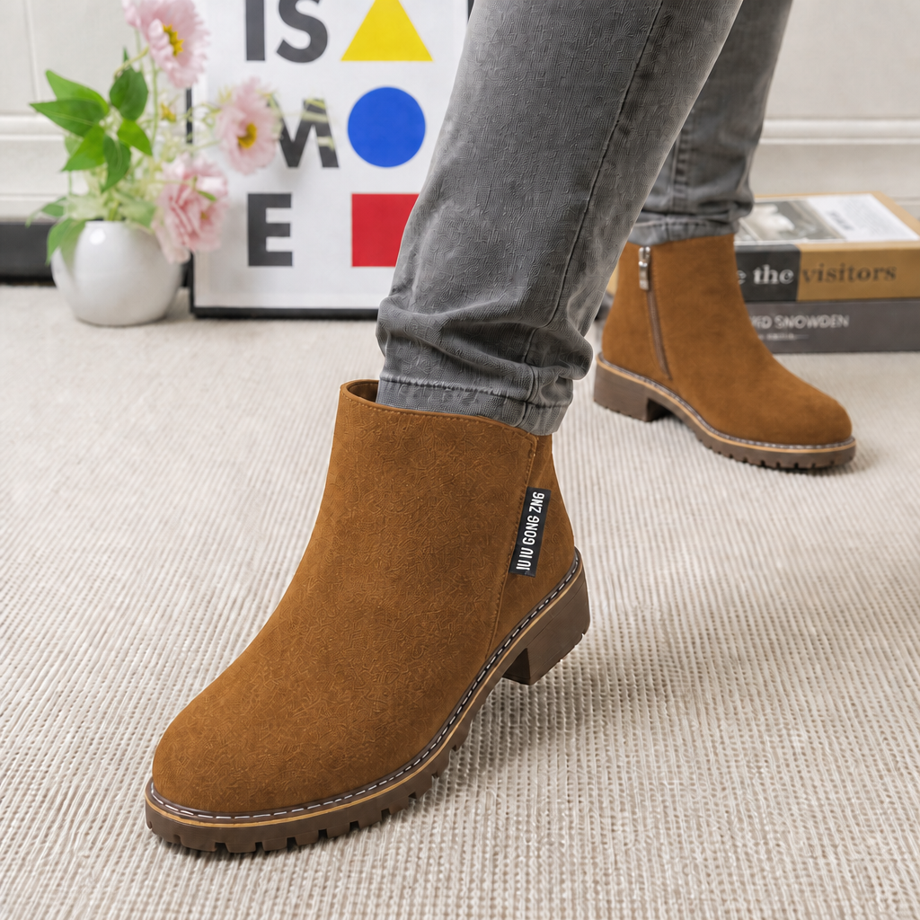 Tan suede ankle boot with a lugged sole, worn with grey jeans
