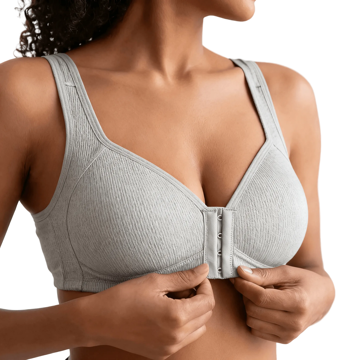 Hands fastening the front closure of a pale grey ribbed bra
