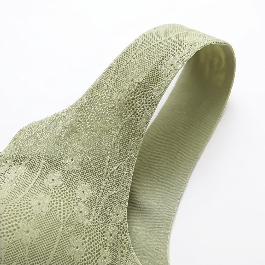 Wide sage lace shoulder strap laid on a white surface