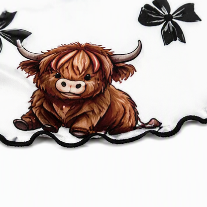 Close-up of the highland cow and bow print on white fabric