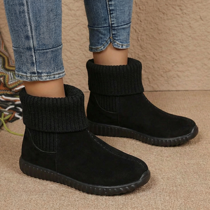 Pair of black knit cuff suede booties worn with cropped jeans