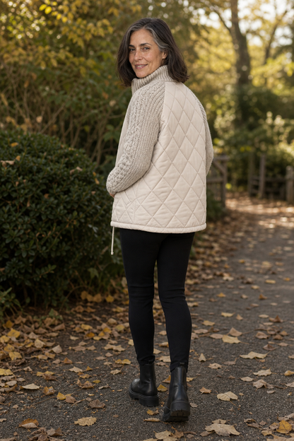 Back view of a cream quilted jacket with cable knit sleeves