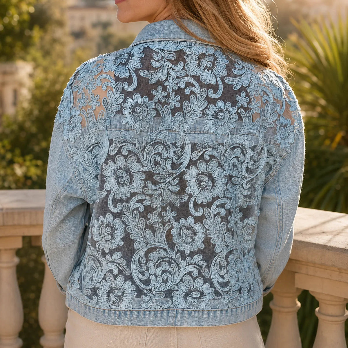 Back view of a denim jacket with a large floral lace panel