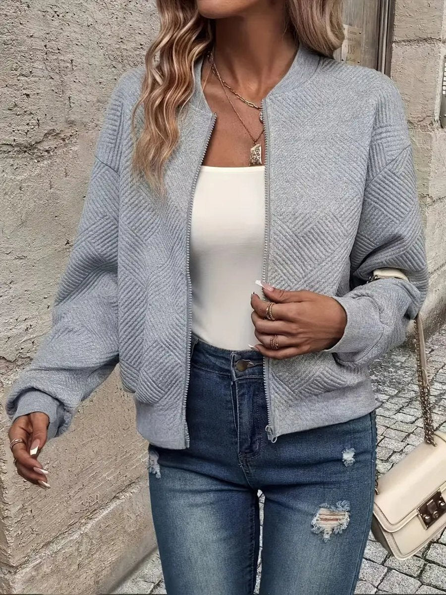 Light grey textured knit zip-up cropped bomber jacket worn over jeans