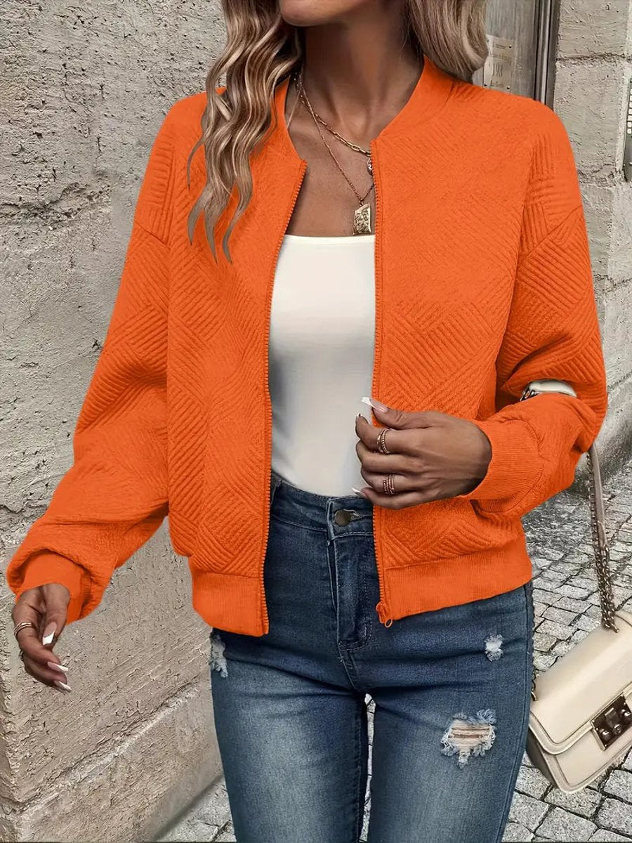 Orange textured knit zip-up cropped bomber jacket worn over jeans