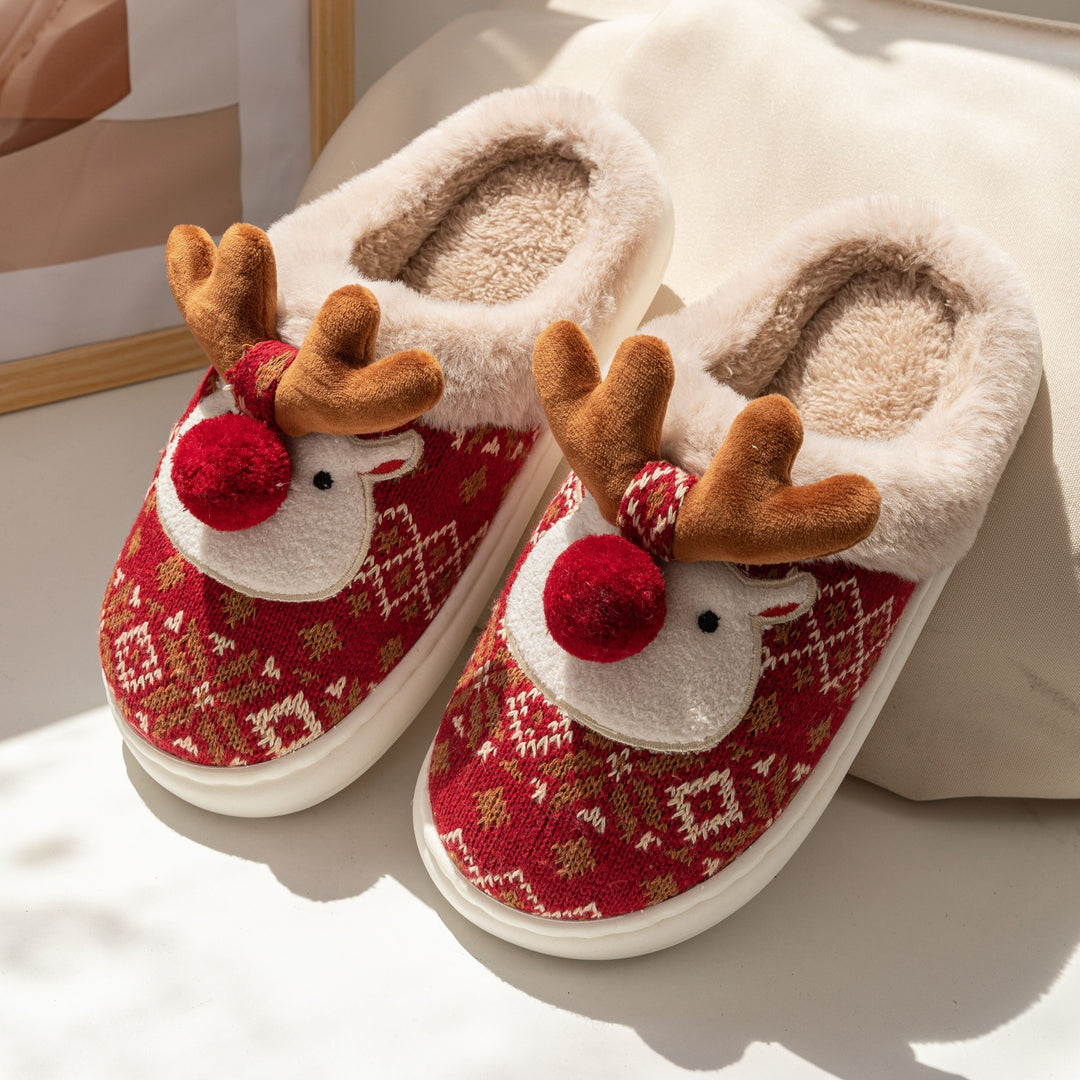 Pair of red reindeer slippers with fur lining, antlers and pom-pom nose in daylight