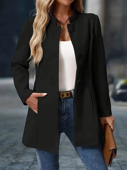 Black stand collar longline coat worn with jeans and a tan clutch