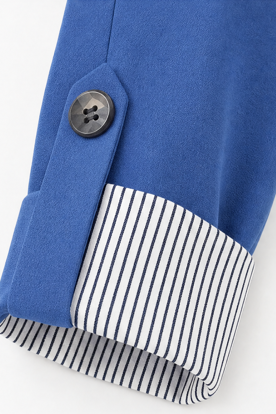 Striped lining revealed in the rolled cuff of a blue blazer