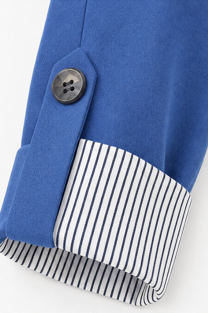 Striped lining revealed in the rolled cuff of a blue blazer